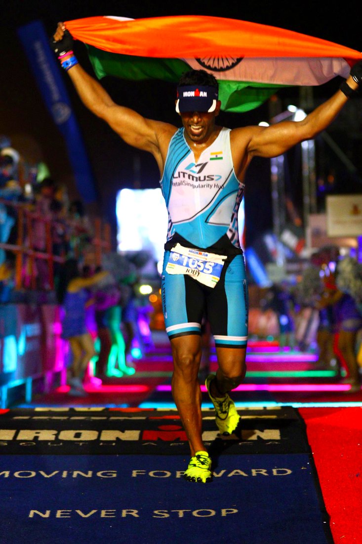 Coach Joby finishing an Ironman at night with the flag